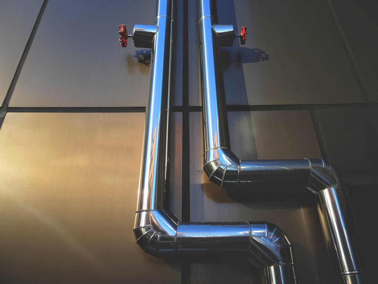 Close-up view of industrial steel pipes with valves on a metallic background, showcasing architecture.